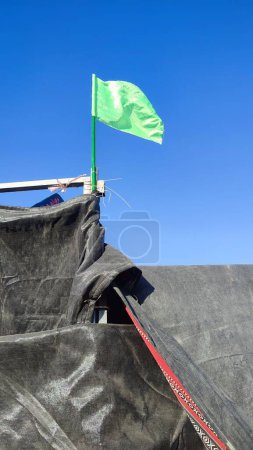 Bandera verde sobre carpa beduina negra, cielo. Foto de alta calidad