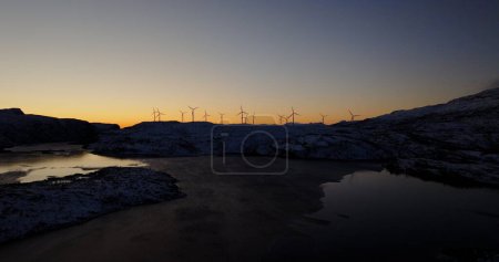 Harmonie in der Dämmerung: Winterlicher Sonnenuntergang und Windräder in Norwegen. Hochwertiges 4k Filmmaterial
