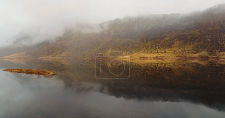 Nebliger Morgen über den ruhigen Fjorden der Lofoten: Eine ruhige Drohnenperspektive auf goldene Herbsttöne, die sich in den ruhigen Gewässern der norwegischen arktischen Wildnis spiegeln. Hochwertiges 4k Filmmaterial