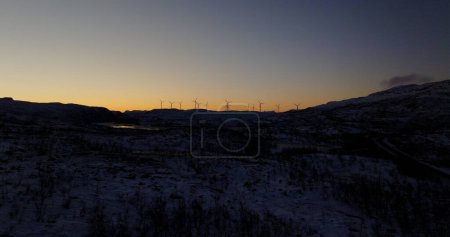 Twilight Silhouettes of Wind Turbines in Snowy Landscape. High quality 4k footage