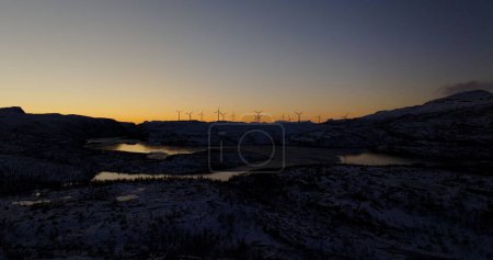 Renewable Dawn: Wind Turbines Silhouetted Against Sunrise in Snowy Norway. High quality 4k footage