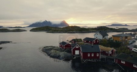Twilight Whisper: Traditional Red Rorbuer Cabins of the Lofoten Archipelago against a Dramatic Mountain Backdrop. High quality 4k footage