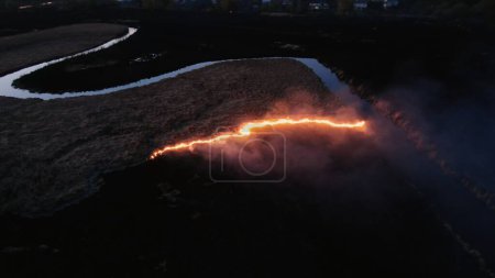 Luftaufnahme des nächtlichen Feuers in der Nähe des Wasserkörpers. Hochwertiges 4k Filmmaterial