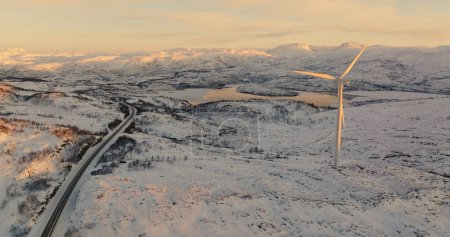 Erneuerbare Energien in der Dämmerung: Windkraftanlage mit Blick auf gewundene Straßen und gefrorene Seen in Norwegen. Hochwertiges 4k Filmmaterial