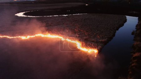 Luftaufnahme des nächtlichen Übergreifens des Feuers auf der Wasserstraße. Hochwertiges 4k Filmmaterial