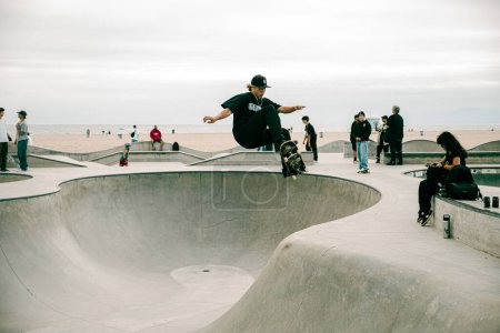 Foto de Venice Beach, CA, Estados Unidos - 17 / 09 / 2023: El patinador realiza una transferencia en un monopatín en el bowl en el skatepark en Venice Beach. - Imagen libre de derechos