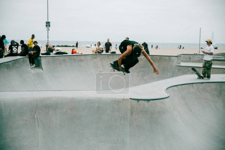 Photo for Venice Beach, CA, USA - Sep 17, 2023: The skater performs a transfer on a skateboard in the bowl at the skatepark on Venice Beach. - Royalty Free Image