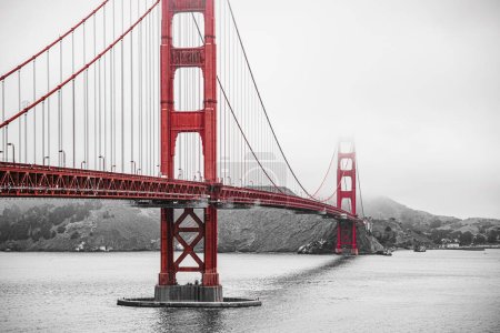 Golden Gate Bridge in San Francisco during foggy weather, a black and white photo with preserved red color.