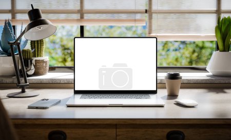 Téléchargez les photos : Un ordinateur portable avec un écran blanc se trouve sur un élégant bureau en bois dans un intérieur de style loft, avec des espaces verts en arrière-plan visibles à travers la fenêtre rendu 3d - en image libre de droit