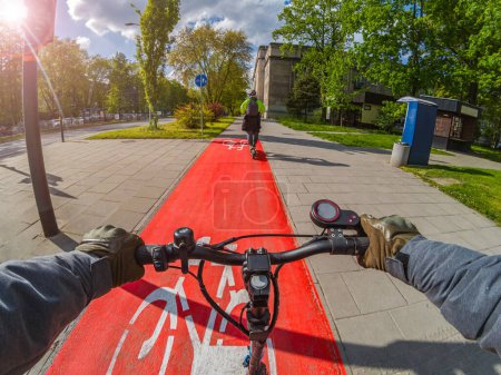 Téléchargez les photos : Monter un scooter électrique sur une piste cyclable par temps ensoleillé. Vue à la première personne. - en image libre de droit