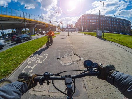 Téléchargez les photos : Monter un scooter électrique sur une piste cyclable par temps ensoleillé. Vue à la première personne. - en image libre de droit