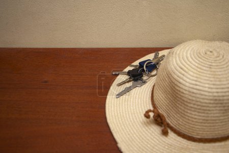 Téléchargez les photos : Chapeau de soleil en paille et clés de la maison sur fond en bois. Concept de quitter la maison, quitter la maison pour les vacances, pour la vocation. - en image libre de droit