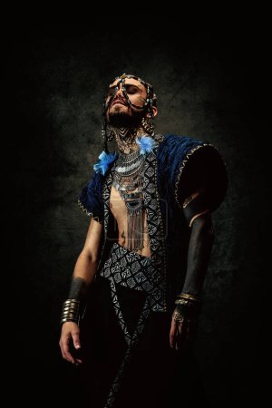 Photo for Tattooed bearded man, wearing ethnic clothing and jewelry - Royalty Free Image