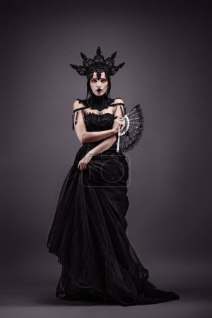 Foto de Atractiva joven con un vestido negro, una corona y un abanico - Imagen libre de derechos