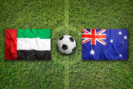 Emiratos Árabes Unidos vs. Australia banderas en el campo de fútbol verde
