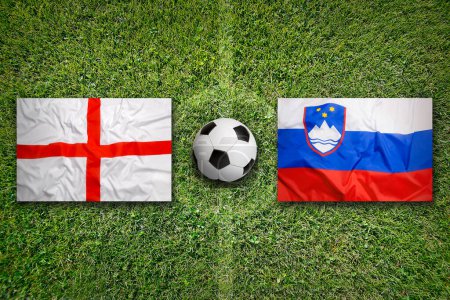 Inglaterra vs. Eslovenia banderas en el campo de fútbol verde
