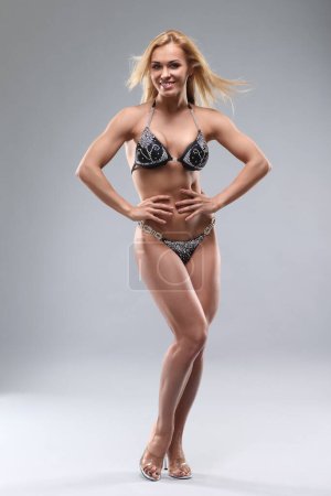 Téléchargez les photos : Athletic woman with beautiful figure in bikini on gray background - en image libre de droit