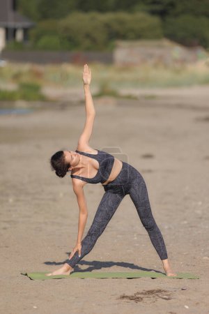 Téléchargez les photos : Jeune femme nue pratique le yoga sur une plage sauvage - en image libre de droit