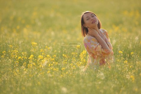 Téléchargez les photos : Jeune femme de beauté dans un champ avec du colza - en image libre de droit