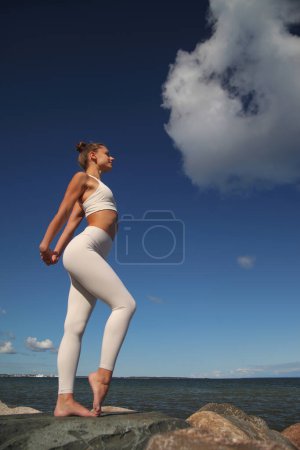 Photo for Young athletic woman in a white tracksuit by the sea - Royalty Free Image