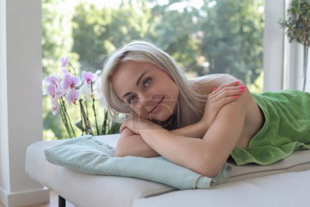 Mujer atractiva y sonriente acostada en una alfombra de masaje

