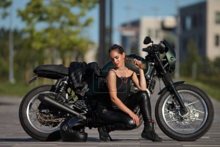 Porträt einer charmanten jungen Frau auf einem schwarzen Motorrad