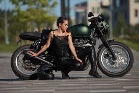 Porträt einer charmanten jungen Frau auf einem schwarzen Motorrad