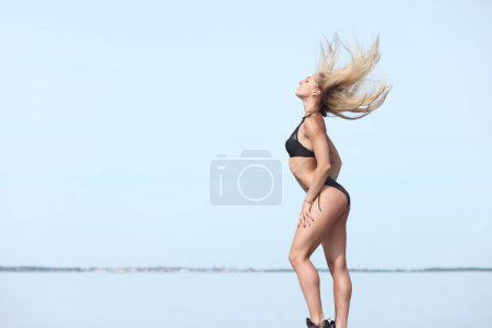 Photo for Young woman in black swimsuit on the beach - Royalty Free Image
