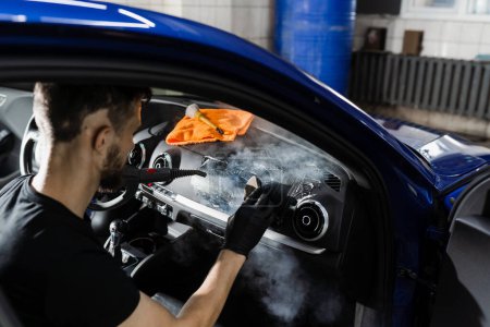 Reinigung des Innenraums mit Schaum und Reinigungsmittel im Auto mittels Dampf. Arbeiter in der Auto-Reinigung sauberes Auto im Inneren. Details im Innenraum des Autos