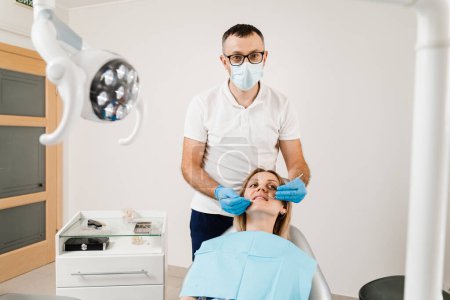 Photo for Consultation with dentist at dentistry. Teeth treatment. Dentist examines girl mouth and teeth and treats toothaches. Happy woman patient of dentistry - Royalty Free Image