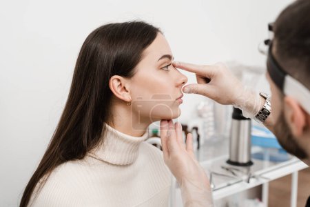 Photo for Septoplasty is surgery to correct deviated septum. Rhinoplasty is reshaping nose surgery for change appearance of the nose and improve breathing. Surgeon is touching and examining girl nose - Royalty Free Image