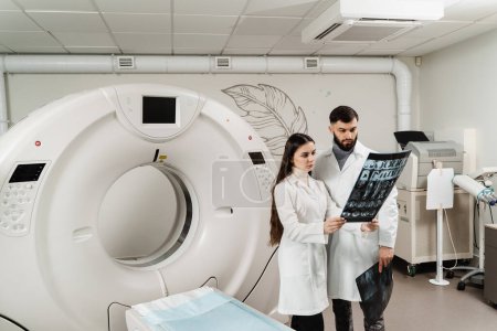 Foto de Dos doctores discutiendo radiografías después de la tomografía computarizada del abdomen del paciente. Tomografía computarizada por TC procedimiento de exploración para obtener imágenes internas detalladas del cuerpo y la investigación sobre tumores en la cabeza, el cerebro y la columna vertebral - Imagen libre de derechos