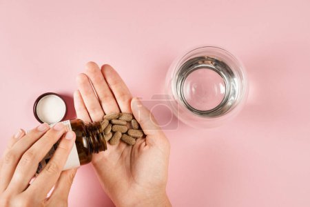 Foto de Tablets of dietary supplements in hand for daily pills intake on pink background. Set of zinc pills, antioxidants from aging, lecithin and adaptogen - Imagen libre de derechos
