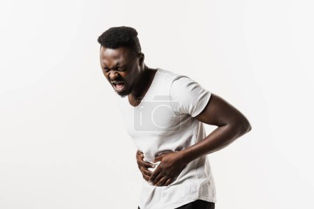 Photo for Ulcer or gastritis stomach ache. Sick african american man hold abdomen because it hurts. Pancreatitis disease of pancreas becomes inflamed - Royalty Free Image