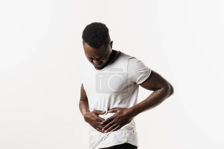 Photo for Sick african american man hold abdomen because it hurts. Stomach pain. Pancreatitis disease of pancreas becomes inflamed - Royalty Free Image