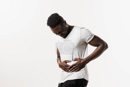 Photo for Sick african american man is holding his stomach because it hurts. Pancreatitis disease of pancreas becomes inflamed. Cancer of stomach and esophagus of African man - Royalty Free Image