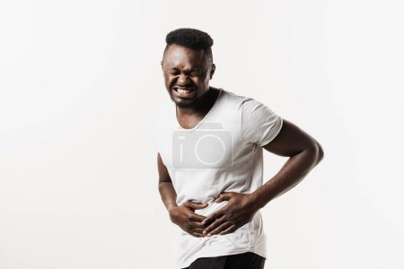 Photo for Stomach pain. Pancreatitis disease of pancreas becomes inflamed. Sick african american man hold abdomen because it hurts - Royalty Free Image