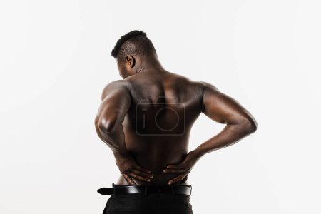 Photo for Kidney infection pyelonephritis urinary tract infection. Muscular african american man feel backache spine pain because of UTI pyelonephritis disease on white background - Royalty Free Image