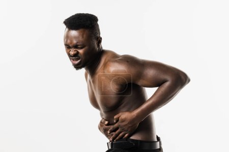 Photo for Appendicitis is inflammation of appendix. Muscular shirtless african american man feel abdominal pain, fever, vomiting, and loss of appetite because of appendicitis inflammation - Royalty Free Image