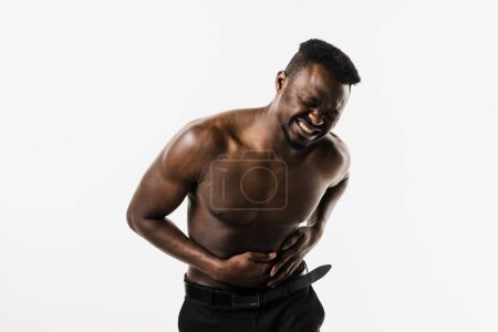 Photo for Appendicitis is inflammation of appendix. Muscular shirtless african american man feel abdominal pain, fever, vomiting, and loss of appetite because of appendicitis inflammation - Royalty Free Image
