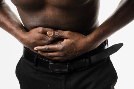 Photo for Stomach pain close-up. Pancreatitis disease of pancreas becomes inflamed. Sick muscular african american man hold abdomen because it hurts - Royalty Free Image