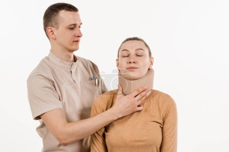 Téléchargez les photos : Traumatologue met un collier souple ou bandage sur la fille pour stabiliser la région cervicale en cas de douleur au cou, blessures et entorses sur fond blanc - en image libre de droit