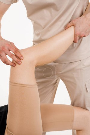 Photo for Knee joint and meniscus injury on white background. Orthopedist is touching and pressing knee for assessment of the volume of physiological movements. Examination of knee mobilisations - Royalty Free Image