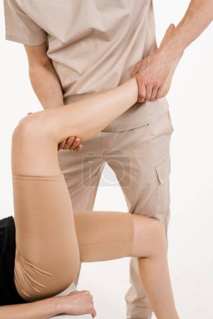 Photo for Orthopedist is touching and pressing knee for assessment of the volume of physiological movements. Examination of knee mobilisations. Knee joint and meniscus injury - Royalty Free Image