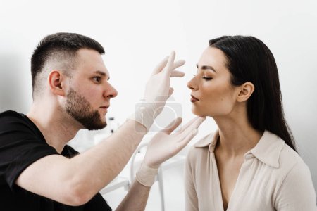 Photo for ENT doctor is touching nose and consulting girl patient in medical clinic before septoplasty surgery. Rhinoplasty is reshaping nose surgery for change appearance of the nose and improve breathing - Royalty Free Image