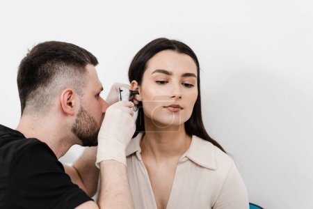 Photo for ENT doctor with otoscope. Otoscopy. Otolaryngologist looks through otoscope the ears of woman. Treatment ear pain - Royalty Free Image