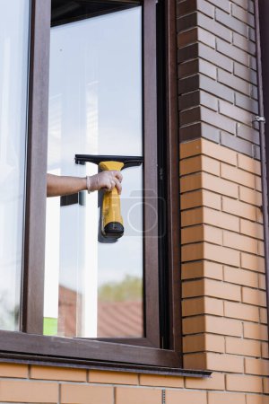 Photo for Process of window washing outside to remove dust, dirt and water. Cleaning window using portable vacuum windows cleaner - Royalty Free Image