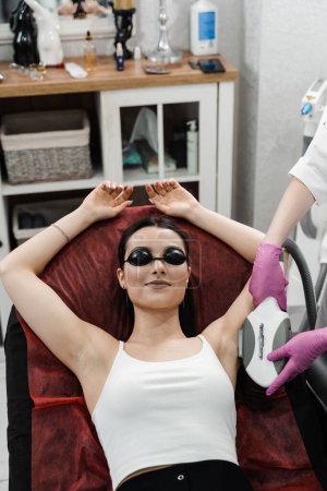 Photo for Beautician is removing armpit hair using elos technology. ELOS electrooptical synergy is combination of light and radio wave energy - Royalty Free Image