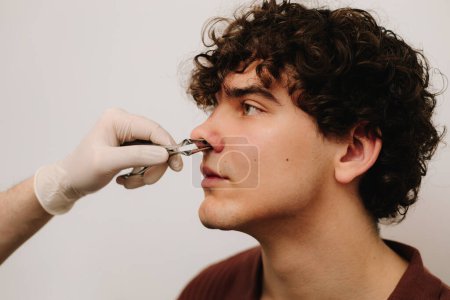 HNO-Arzt untersucht Nase des Patienten mit Rhinoskop. Nasenspiegelung in einer privaten HNO-Klinik vor Nasenkorrektur oder Septoplastik