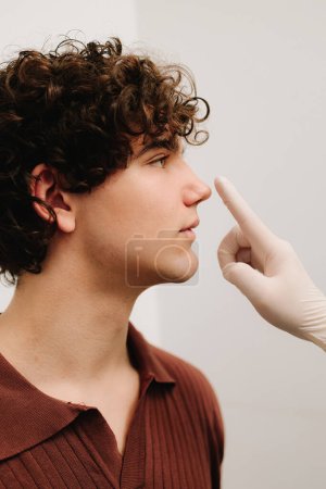 Rhinoplastie consultation pour l'homme avant la chirurgie plastique pour corriger la taille et la forme du nez. Rhinoplastie remodelant nez et septoplastie. ORL médecin toucher le nez du patient avant la rhinoplastie